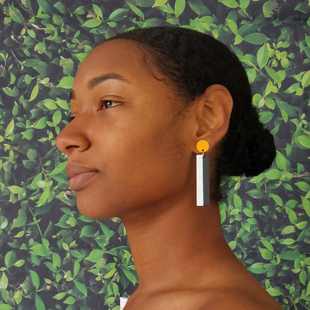 Model wearing geometric yellow, white, and black color blocked statement earrings by the brand SCOTCHBONNET.