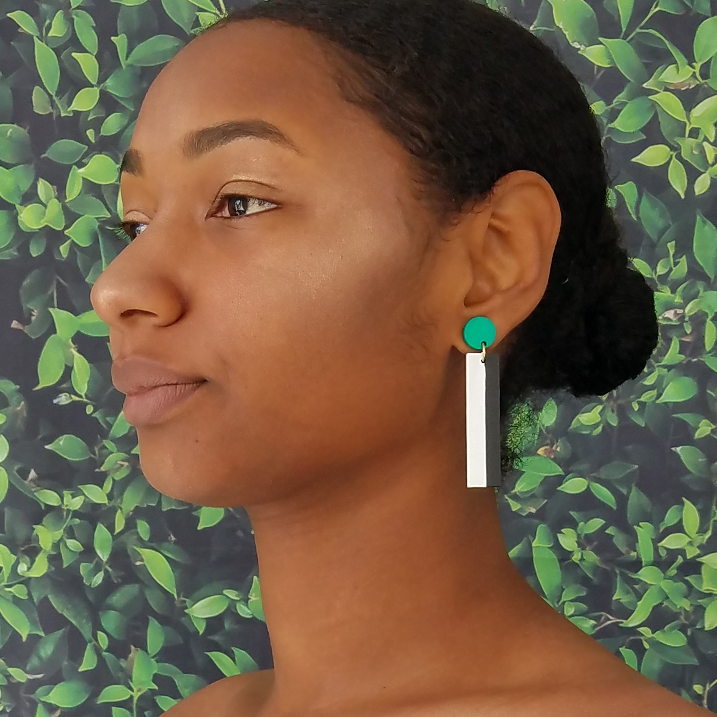 Model wearing geometric teal, white, and black color blocked statement earrings by the brand SCOTCHBONNET.