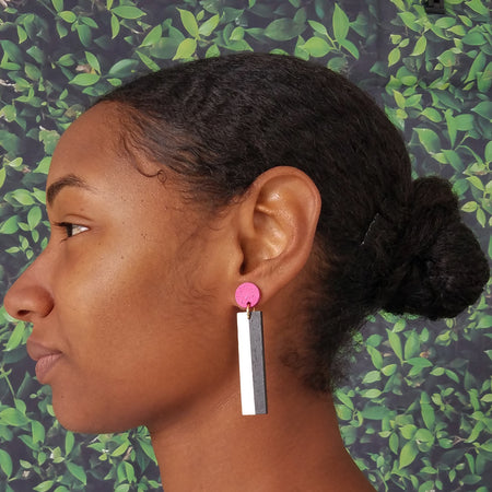 Model wearing geometric magenta, white, and black color blocked statement earrings by the brand SCOTCHBONNET.
