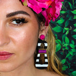 Model with floral crown wearing modern, curvy, black and white striped statement earrings with hand-beaded magenta accents by the brand SCOTCHBONNET.