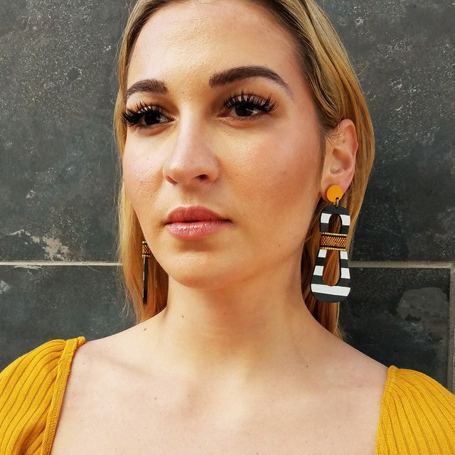 Front view of model wearing modern, curvy, black and white striped statement earrings with hand-beaded yellow accents by the brand SCOTCHBONNET.