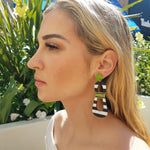Model with blonde hair wearing modern, curvy, black and white striped statement earrings with hand-beaded chartreuse accents by the brand SCOTCHBONNET.
