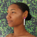 Model wearing geometric purple, white, and black color blocked statement earrings by the brand SCOTCHBONNET.