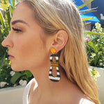 Model wearing modern, curvy, black and white striped statement earrings with hand-beaded yellow accents by the brand SCOTCHBONNET.
