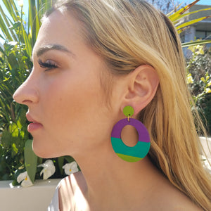 Model with blonde hair wearing large, round, chartreuse, teal and purple color blocked neutral tone statement earrings by the brand SCOTCHBONNET.