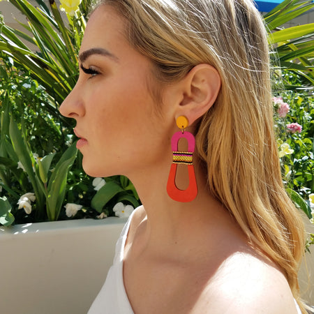 Side view of model wearing modern, curvy, yellow, magenta and orange color blocked statement earrings with hand-beaded accents by the brand SCOTCHBONNET.