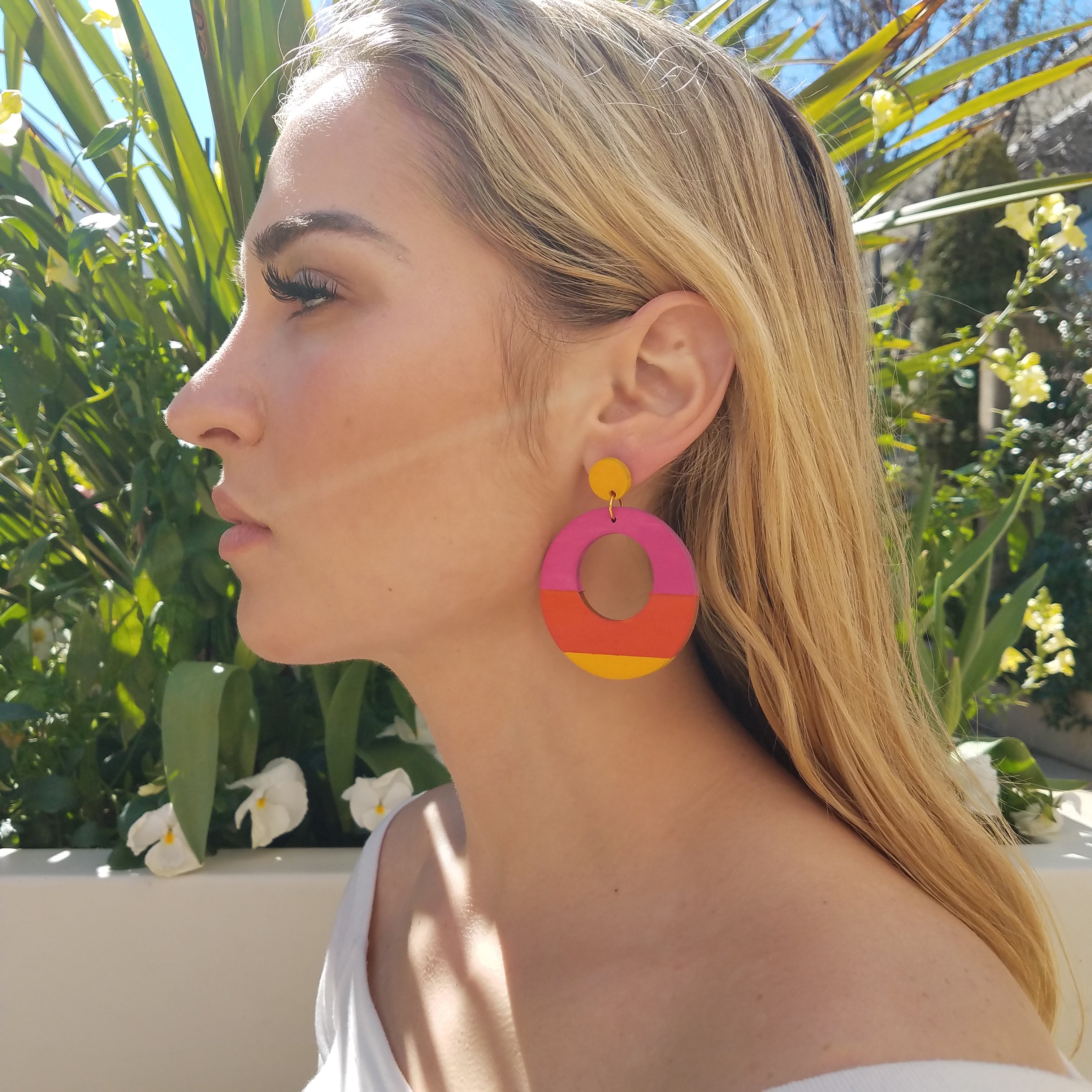 Side view of model wearing large, round, yellow, magenta and orange color blocked neutral tone statement earrings by the brand SCOTCHBONNET.
