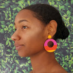 Model wearing large, round, yellow, magenta and orange color blocked neutral tone statement earrings by the brand SCOTCHBONNET.