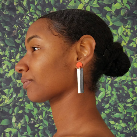 Model wearing geometric orange, white, and black color blocked statement earrings by the brand SCOTCHBONNET.